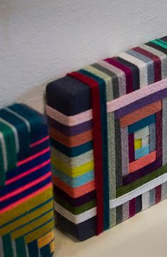 several colorful striped coasters are lined up against a white wall and one is on the floor