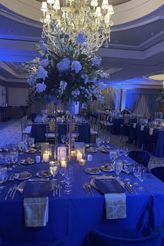 a table is set up with blue linens and silver place settings for an event