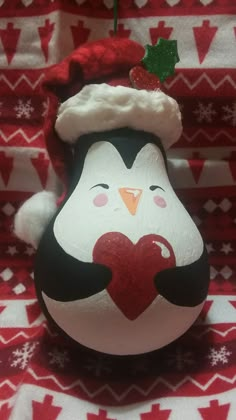 a penguin ornament with a santa hat and heart on it's chest