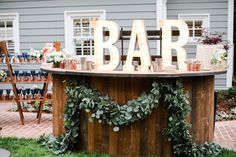 an outdoor bar decorated with greenery and lighted letters