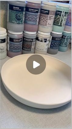 a white plate sitting on top of a counter next to some paint cans in front of it