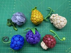 five plastic fruits sitting on top of a green cutting board