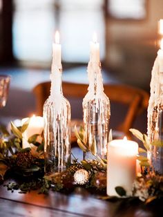 candles are lit on the table in front of wine bottles