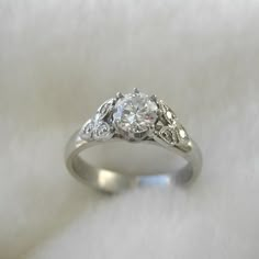 a white gold ring with three diamonds on it, sitting on top of a white cloth