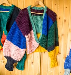 multicolored sweaters hanging on a wooden wall