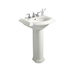 a white pedestal sink with two faucets