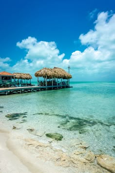 the water is crystal blue and clear with some straw umbrellas on it's roof