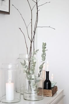 candles and branches in glass vases on a table