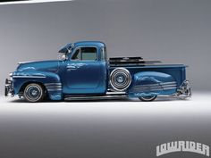 an old blue pickup truck with chrome rims