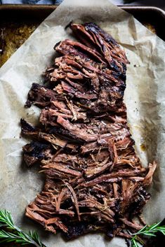 sliced up meat sitting on top of a piece of parchment paper next to a sprig of rosemary