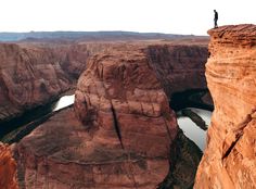 a man standing on the edge of a cliff overlooking a river and canyon below him