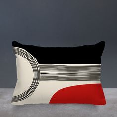 a black, white and red pillow sitting on top of a gray floor next to a wall