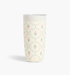 a white coffee cup with floral designs on the front and sides, sitting against a white background