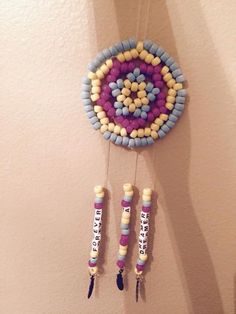 a colorful beaded dream catcher hanging on the wall next to two crayons