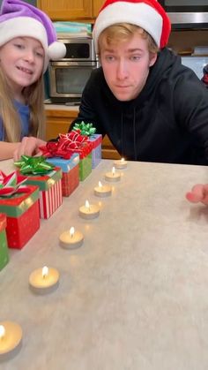 two young children sitting at a table with presents and lit candles in front of them