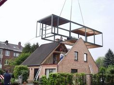 a house being lifted by a crane with people on the roof and in the air