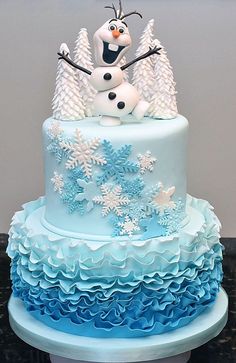 a three tiered cake decorated with frosting and snowflakes