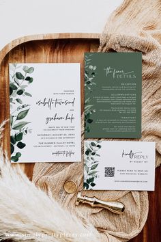 the wedding stationery is laid out on a wooden tray with greenery and calligraphy