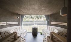 an empty wooden bench sitting in the middle of a room filled with white benches and round lights