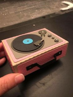 a hand is pointing at an old fashioned record player that has been turned pink and blue