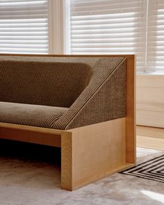 a couch sitting in front of a window with blinds on the windowsill and carpeted floor