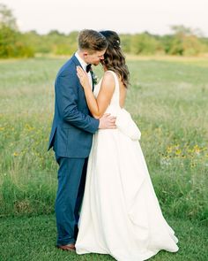 a bride and groom kissing in a field