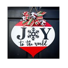 a joy to the world ornament hanging on a black door with red, white and green ribbon