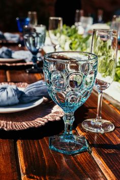 an empty wine glass sitting on top of a wooden table next to plates and napkins