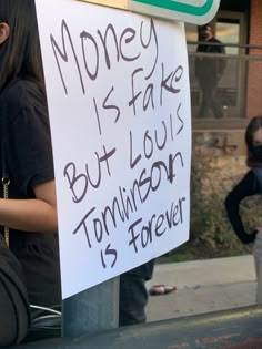 a woman holding a sign that says money is fake but louis is ferguson is forever