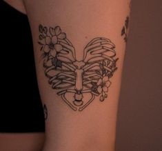 a woman's arm with a tattoo on it that has flowers in the shape of a heart