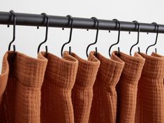 four pairs of socks hanging from a black metal rail with hooks on it and two orange ones in the foreground