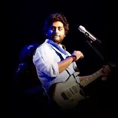 a man holding a guitar while standing in front of a microphone