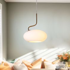 a living room filled with furniture and a white light hanging from the ceiling above it