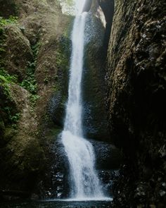 there is a waterfall in the middle of some rocks and water flowing down it's sides