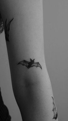 a woman's arm with a bat tattoo on the left side of her arm