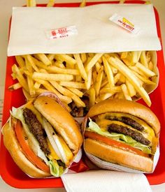 two hamburgers and fries in a red tray