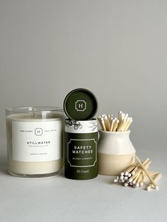 a candle and some matches sitting next to each other on a white surface with grey background