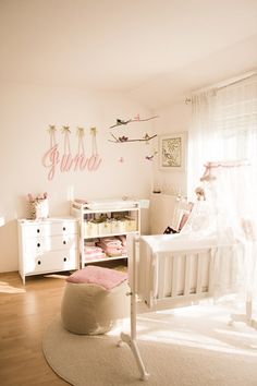 a baby's room with white furniture and pink accessories on the walls, including a crib