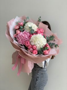 a woman holding a bouquet of flowers in her hands with pink and white blooms on it