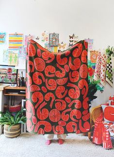 a woman standing in front of a red and black blanket on top of a white rug