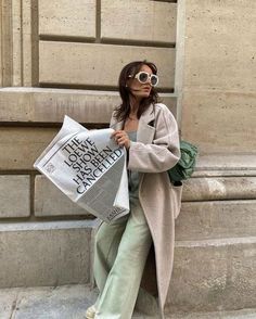 a woman is walking down the street with a newspaper in her hand and sunglasses on