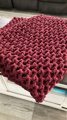 a crocheted blanket is sitting on the floor next to a window sill