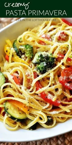 a plate of pasta with broccoli, peppers and zucchini on it