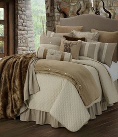 a bed with pillows and blankets on it in front of a brick wall next to a window