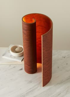 two wooden vases sitting on top of a white table next to a book and bowl