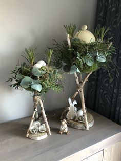 two small trees with plants in them on top of a dresser