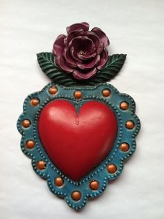 a red heart shaped object with a flower on top