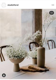 two vases filled with baby's breath sitting on top of a table