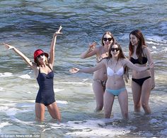 three women in bathing suits are standing in the water