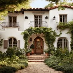 a white house with lots of greenery on the front door and steps leading up to it